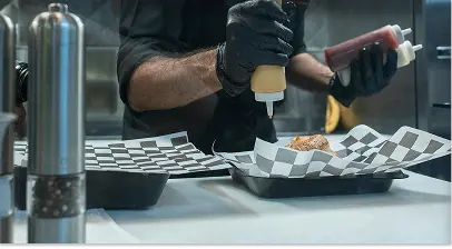 Kitchen cook adding condiments to food